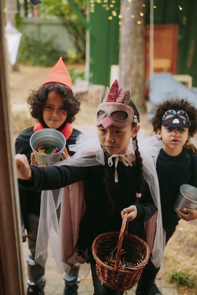 children wearing different costumes knocking on a door trick or treating