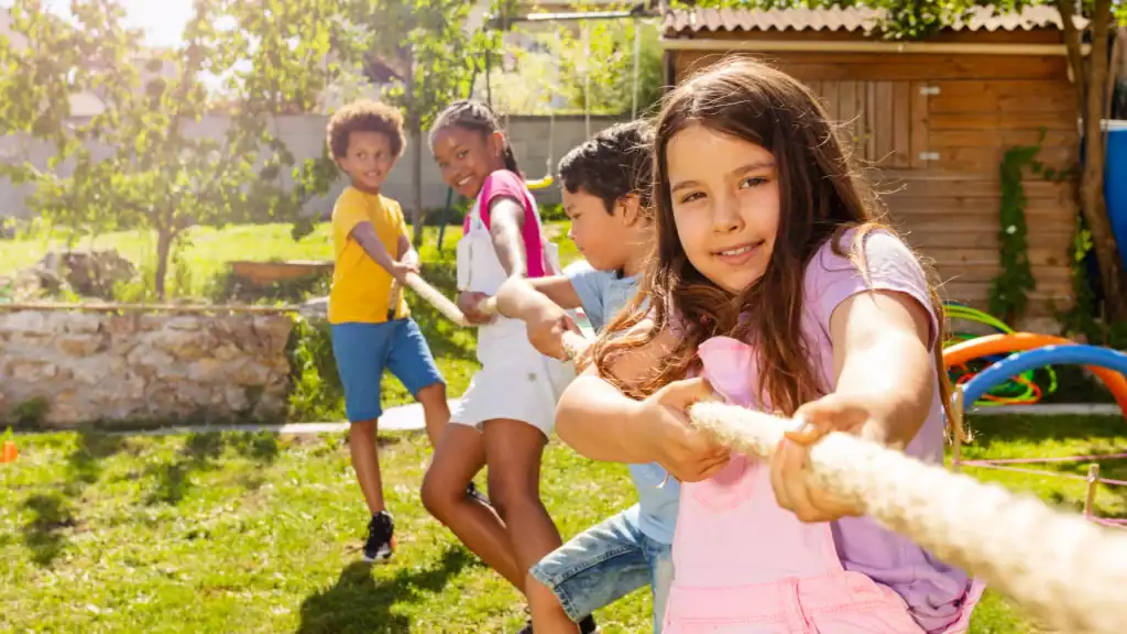 Diverse group of young children playing tug-of-war outdoors
